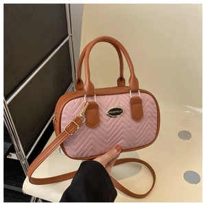 Detail of pink and brown quilted handbag showing V-shaped stitching and golden hardware