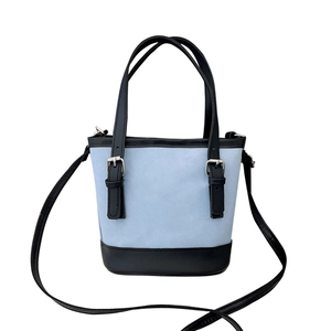 Blue canvas bucket bag with black leather trim and adjustable straps for crossbody use