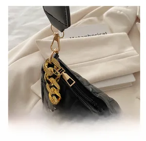 Detail of smooth metal zipper and gold chain hardware on black quilted shoulder bag
