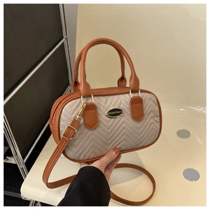 Detail of cream quilted handbag with brown leather trim and golden hardware buckle