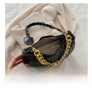 Detail of black quilted leather shoulder bag with gold chunky chain and braided handle