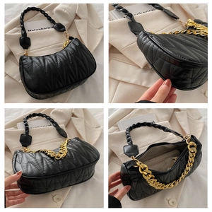 Detail of black quilted shoulder bag featuring woven strap and chunky gold metal chain