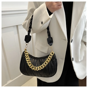 Detail of black quilted hobo bag featuring decorative thick gold chain and woven strap