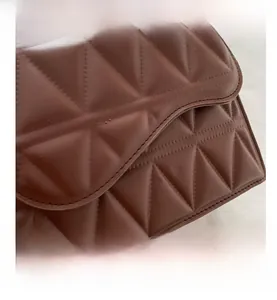 Dettaglio ravvicinato della borsa in pelle marrone con cuciture geometriche e trama fine