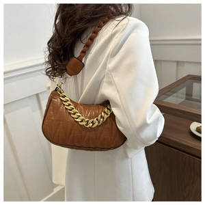 Close-up of brown quilted underarm bag with gold chain and woven strap detail