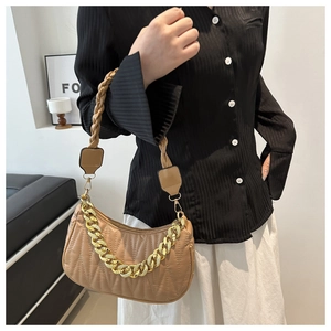 Shoulder bag detail with woven strap and bold gold chain on camel quilted leather