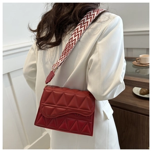Dettaglio borsa quadrata rossa trapuntata con ampia tracolla a motivi geometrici chic