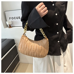 Detail of khaki quilted shoulder bag featuring gold chain strap and wavy stitching