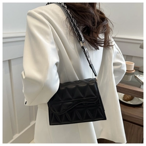 Borsa quadrata trapuntata nera con tracolla geometrica larga indossata dalla modella