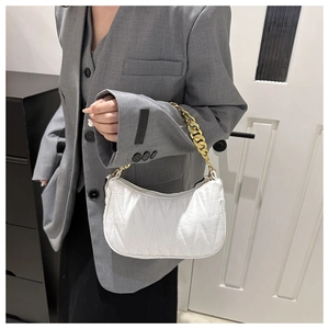 Detail of white quilted baguette bag with chunky gold chain strap and wave stitching