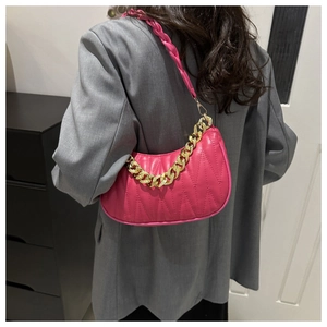 Detail of hot pink crescent bag featuring wavy quilting and a gold chain shoulder strap