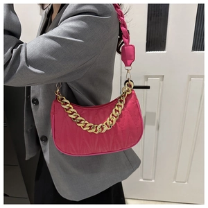 Detail of fuchsia quilted shoulder bag with gold chain and woven strap on a model