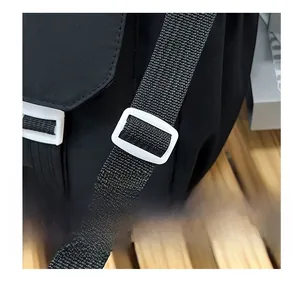 Detail of adjustable white plastic buckle on a black nylon crossbody bag shoulder strap