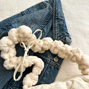 Detail of white plush ruffled shoulder strap on soft faux fur bag with drawstring