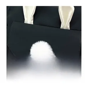 Close-up of black nylon crossbody bag with cute white bunny ears and plush ball detail