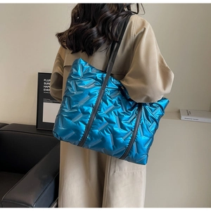 Side view of oversized bright blue metallic puffer tote bag with quilted details