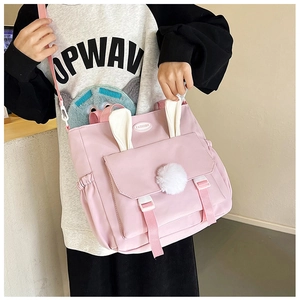 Close-up of pink nylon shoulder bag with white rabbit ears and plush ball charm details