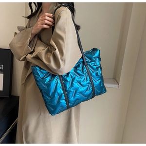 Quilted electric blue tote bag with metallic down-like texture shown on a model
