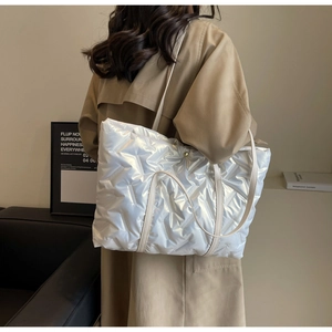 Detail of white quilted tote bag with pearl finish and long shoulder straps
