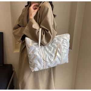 Macro view of silver quilted tote bag showing high-gloss metallic fabric and texture