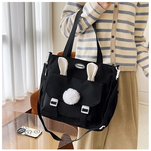 Detail of black nylon tote bag featuring cute bunny ears and fashion label with shoulder strap