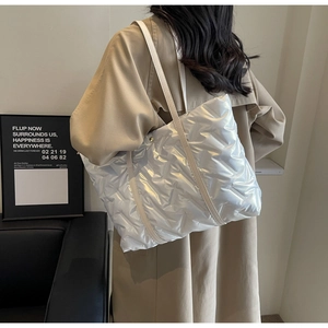 Detailed view of silver down tote bag with V-shaped quilting and glossy nylon texture