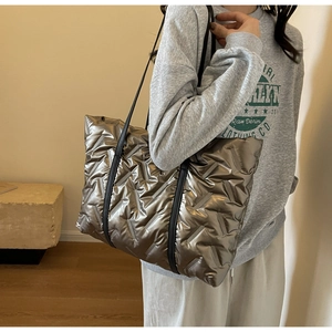 Macro detail of quilted puffer tote bag in metallic bronze finish with black straps