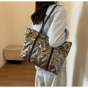 Detail view of a metallic tote bag with geometric quilting worn by a model