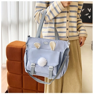 Detail of light blue cute tote bag with rabbit ears and plush ball on a fashion model