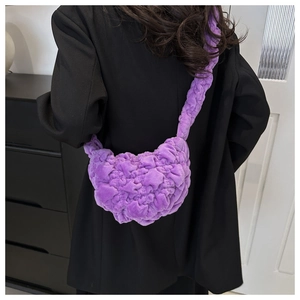 Detail of a purple plush pleated shoulder bag with soft faux fur texture on a model