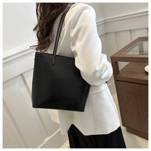 Detail view of a black vintage bucket bag featuring matte leather texture on a female model