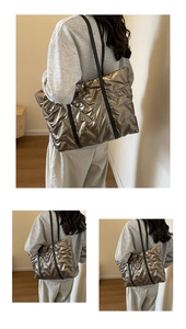 Detail of metallic quilted tote bag with bronze reflective finish and black leather straps
