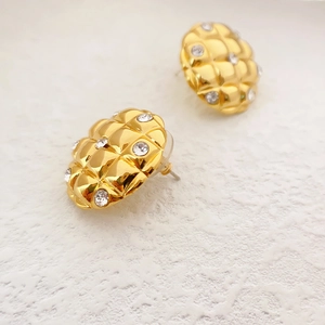 Macro view of gold pineapple style quilted earrings with sparkling crystal accents