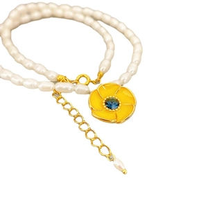 Elegante collana di perle con ciondolo a fiore giallo e gemma blu centrale