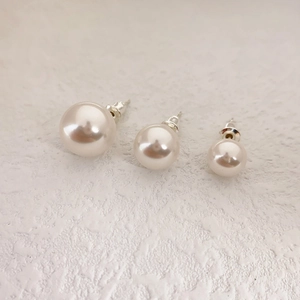 Three-piece set of high-luster round pearl stud earrings in varying sizes on white surface
