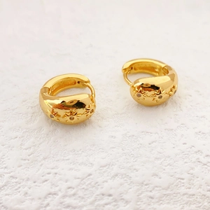 Boucles d'oreilles créoles dorées avec étoiles embossées et zircons sur fond blanc