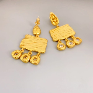 Detail of vintage golden stud earrings with hammered texture and three zircon drops