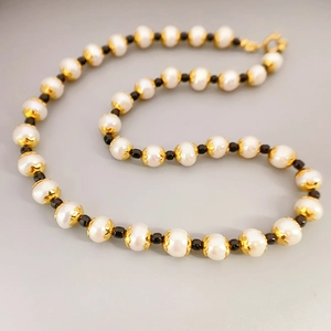 Elegant freshwater pearl necklace with gold floral spacers and black beads on grey background