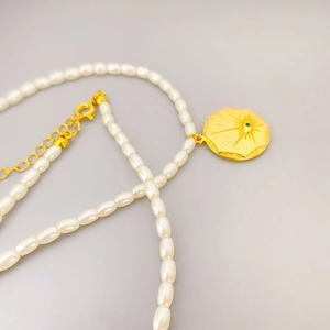 Rice pearl necklace with 18K gold-plated sunburst pendant and green gemstone inlay