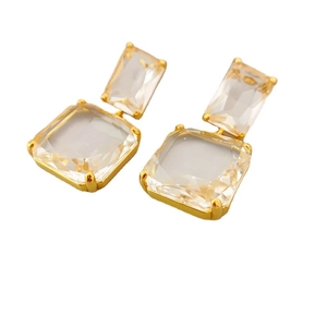 Elegante geometrische Ohrhänger mit klaren Edelsteinen in Goldfassung auf weißem Grund