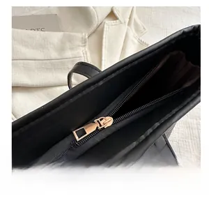 Detail of smooth gold zipper on black quilted tote bag with elegant V-shaped stitching