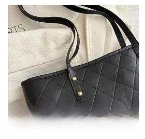 Detailed close-up of black quilted leather texture and gold stud accents on a tote bag