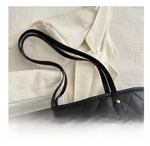 Detail of black quilted tote bag with golden rivets and slim leather shoulder straps
