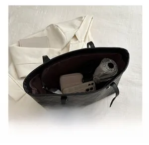 Macro detail of spacious interior in quilted black tote bag with everyday essentials