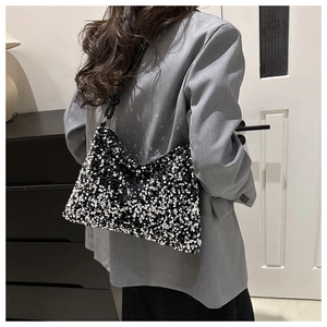 Détail d'un sac hobo à paillettes noires et argentées sur l'épaule d'un mannequin