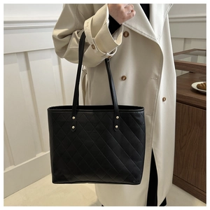 Detail of black quilted tote bag with gold rivets and spacious leather interior