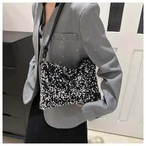 Sac à bandoulière chic à paillettes noires et argentées porté par un mannequin en costume