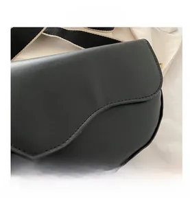 Detail of black leather saddle bag showing fine stitching and bicolor wide strap