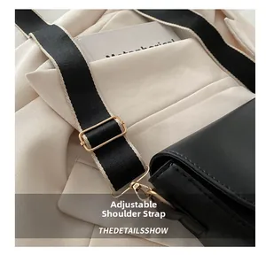 Detail of adjustable woven black and beige strap with gold buckles on saddle bag