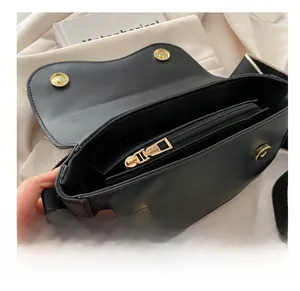 Detail of minimalist black saddle bag showing smooth zipper and internal storage space